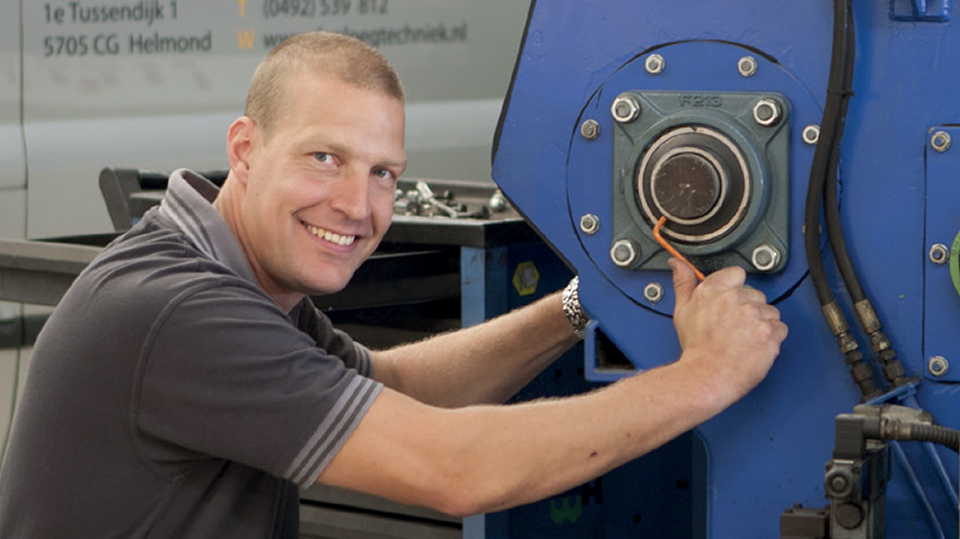 Man die aan het sleutelen is aan een machine